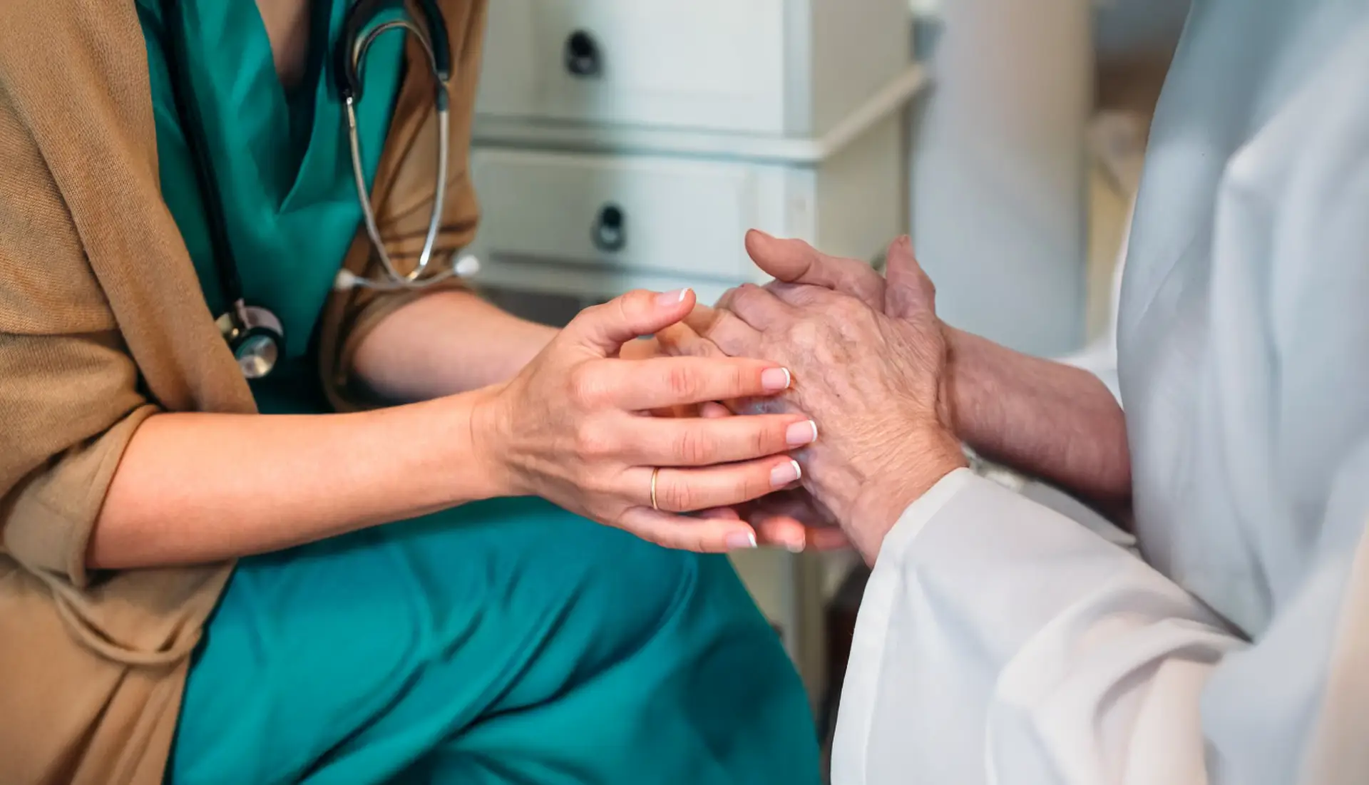 Caregiver comforting aging loved one at home—support for emotional well-being and palliative care